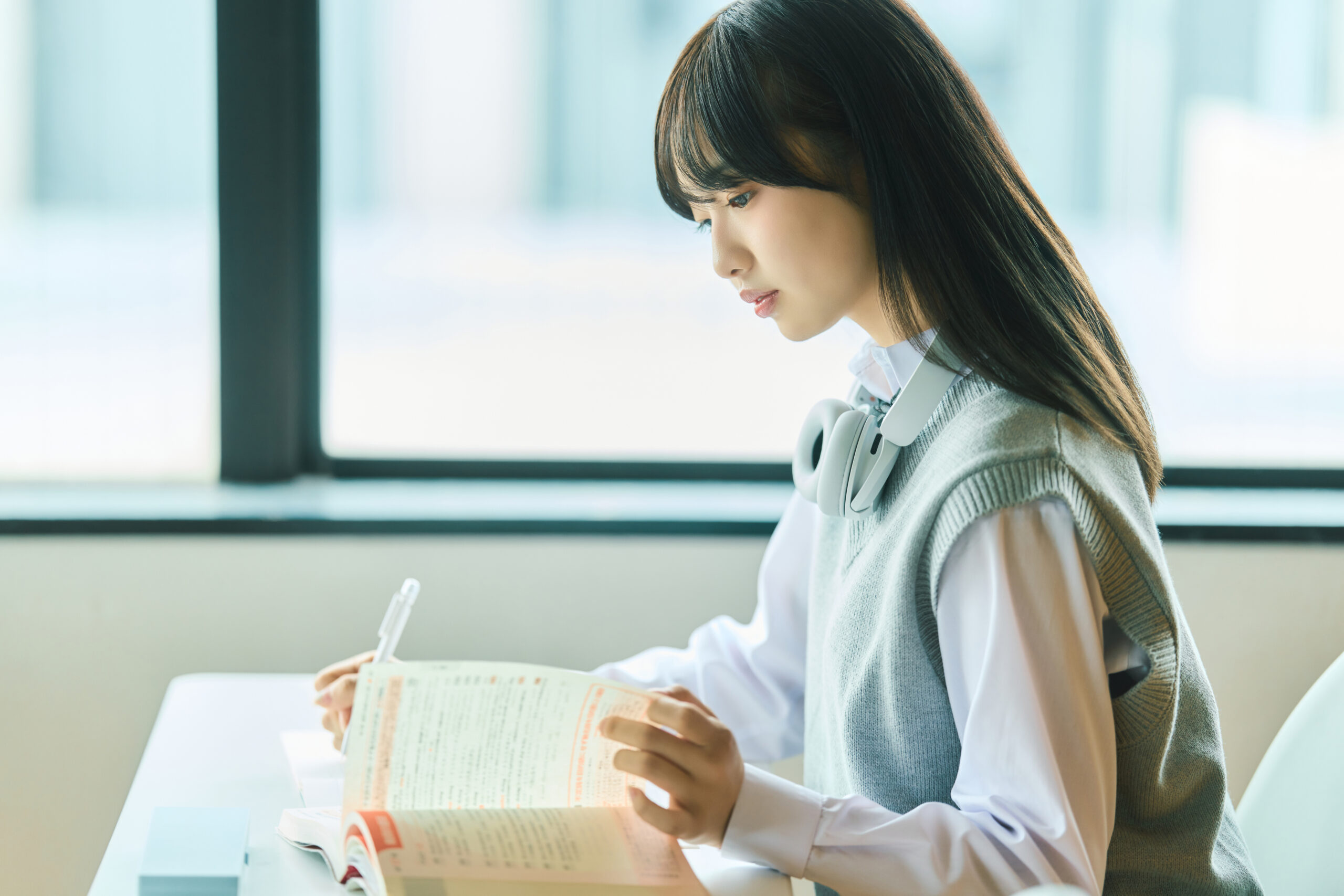窓辺で教材を開き、自分で学習を進める高校生