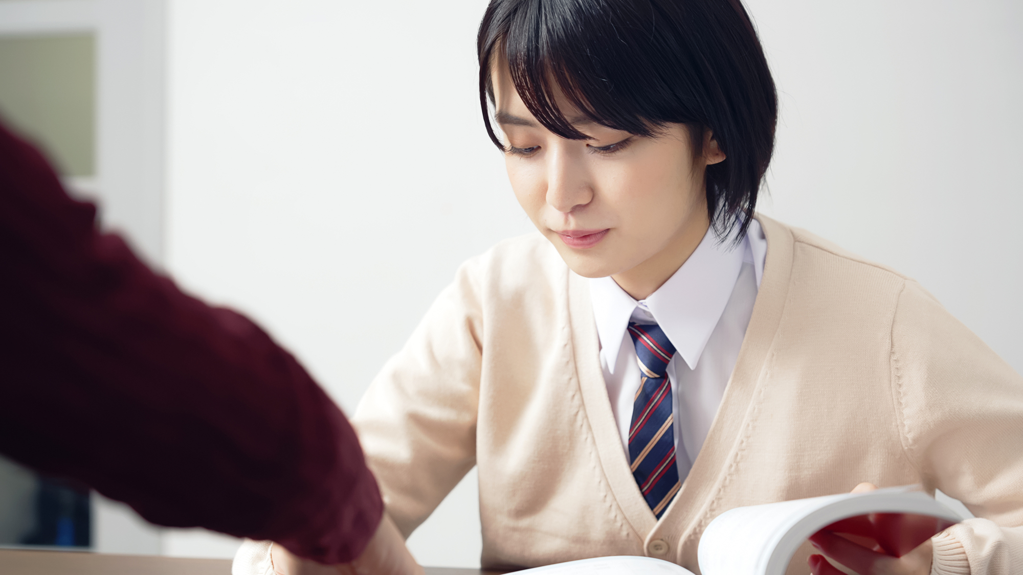 教材を開き、相手に質問しながら学習する高校生